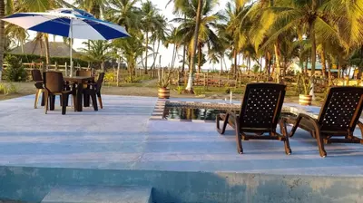 a table with chairs and an umbrella next to a pool at Cabaña Olas Del Mar in San Bernardo del Viento