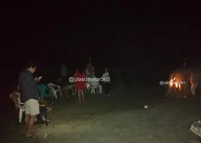 a group of people standing around a fire at night at Cabaña Olas Del Mar in San Bernardo del Viento