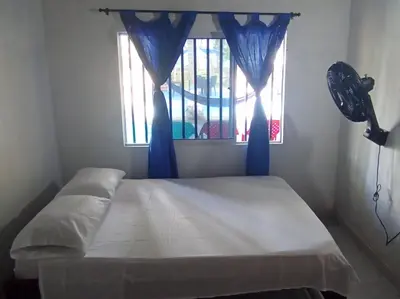 a bedroom with a bed with blue curtains and a window at Cabaña Olas Del Mar in San Bernardo del Viento