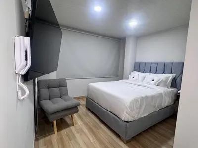a bedroom with a bed and a chair and a phone at Hospedaje Casa Rueda in Barranquilla