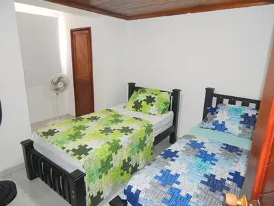 a bedroom with two beds and a fan at Apartment Nurita Boston in Barranquilla
