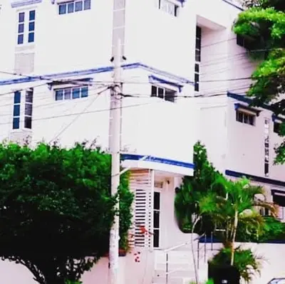 a tall white building with trees in front of it at Los Prados Vip in Barranquilla