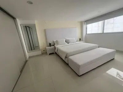 a white bedroom with two beds and a window at Gloria Al Laguito Duplex in Cartagena de Indias