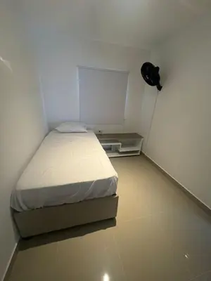 a small white room with a bed and a fan at Apartamentos Cartagena Acuarium in Cartagena de Indias