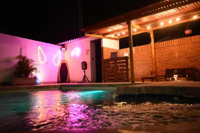 a swimming pool at night with pink and purple lights at Cabaña la casa de vero in Santa Veronica