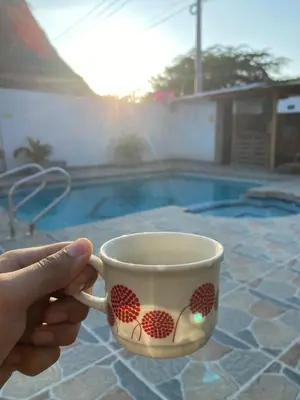 a person holding a coffee cup in front of a pool at Cabaña la casa de vero in Santa Veronica