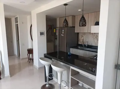 a kitchen with a black counter and stools in it at apartamento Amazilia en alameda del rio in Barranquilla