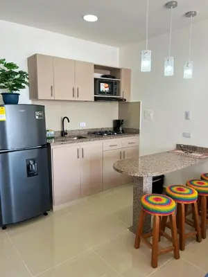 a kitchen with a refrigerator and a counter with stools at Cartagena Aparta Suite con Vista al Mar in Cartagena de Indias