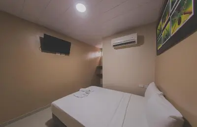 a small room with a bed and a tv at Hotel Boquilla Suites By GEH Suites in Cartagena de Indias