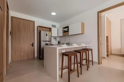 a kitchen with a white counter and some stools at Lujoso A Estrenar/Oasis Laguna Cristalina 2BR in Los Arrayanes
