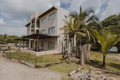 a white building with palm trees in front of it at Apartamento Atlantic 211 in La Perdiz