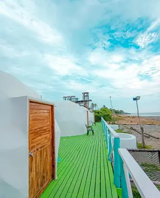 a balcony with a wooden door and a view of the beach at Barracuda Glamping in Paso Nuevo