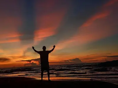 a man standing on the beach with his arms up at Barracuda Glamping in Paso Nuevo