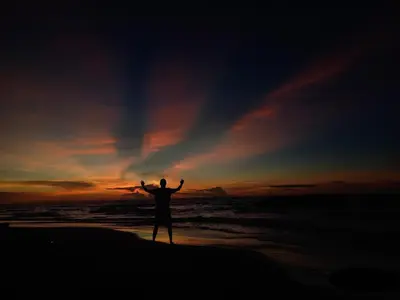 a man standing on the beach with his arms up at Barracuda Glamping in Paso Nuevo
