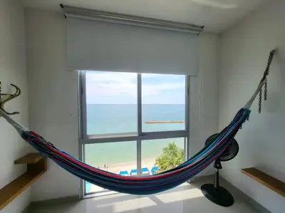 a hammock in a room with a view of the beach at Apartamentos Mi Reserva OK - Bahía Marina in Coveñas