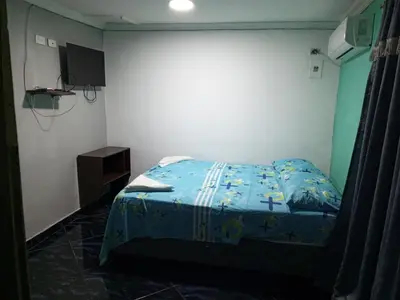 a bedroom with a bed with a blue comforter at Sharly House in Cartagena de Indias