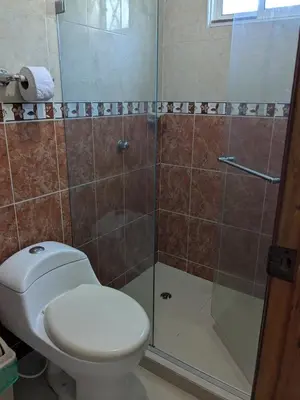 a bathroom with a toilet and a glass shower at Me Quedo Aqui, Casa Cerca del Aeropuerto de Cartagena! in Cartagena de Indias