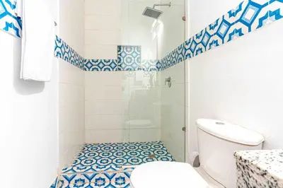 a bathroom with a toilet and a shower with blue and white tiles at Luxury Bryon Pool in Cartagena de Indias