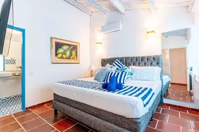 a bedroom with a large bed with blue and white pillows at Luxury Bryon Pool in Cartagena de Indias