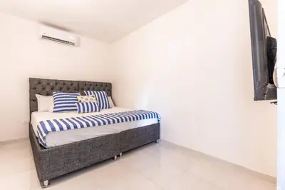a bedroom with a bed with blue and white striped pillows at Luxury Bryon Pool in Cartagena de Indias