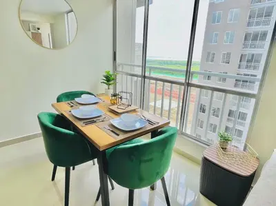 a table with green chairs in a room with a window at Tropical Oasis Barranquilla in Barranquilla