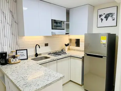 a kitchen with white cabinets and a stainless steel refrigerator at Tropical Oasis Barranquilla in Barranquilla
