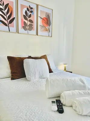 a white bed with two remote controls on it at Tropical Oasis Barranquilla in Barranquilla