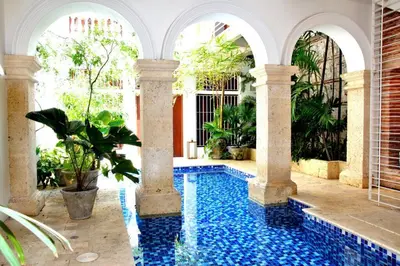 a swimming pool in the middle of a house with columns at Charming 1BR apartment in the Heart of Cartagena's Old City in Cartagena de Indias