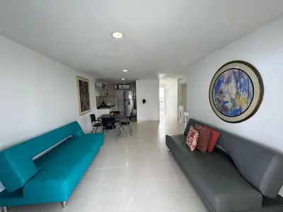 a living room with a blue couch and a dining room at Apartamentos En Edificio Portofino ICDI in Cartagena de Indias