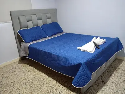 a bed with blue sheets and two white towels on it at El reposo real in Barranquilla