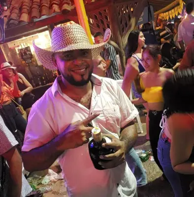 a man wearing a pink shirt and a cowboy hat at mar azul in Cartagena de Indias