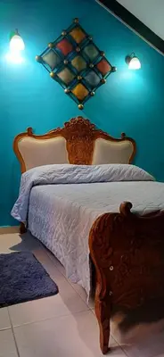 a bedroom with a wooden bed with a blue wall at Habitación con baño privado en el corazón de Manga in Cartagena de Indias