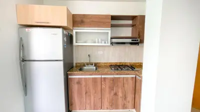 a kitchen with a white refrigerator and wooden cabinets at Hermoso Apartamento Frente al Mar 2 Habitaciones B12A in Coveñas