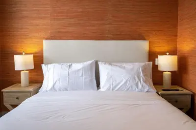 a bed with white sheets and pillows and two lamps at Hermoso moderno y comodo Cartagena Beach CB741 in Cartagena de Indias