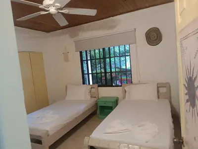 two beds in a room with a ceiling fan at Casa Luna in Santa Veronica