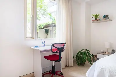 a red chair in a bedroom with a window at Walled City apt- Rooftop Pool & Private Garden in Cartagena de Indias