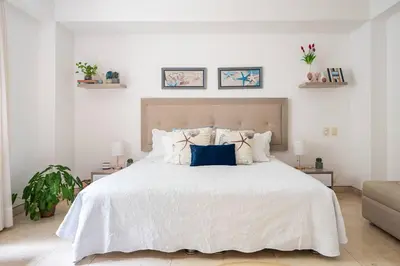 a white bedroom with a large white bed with pillows at Walled City apt- Rooftop Pool & Private Garden in Cartagena de Indias