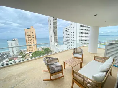 a balcony with a couch and chairs and a view of the ocean at Melodias de Verano in Cartagena de Indias