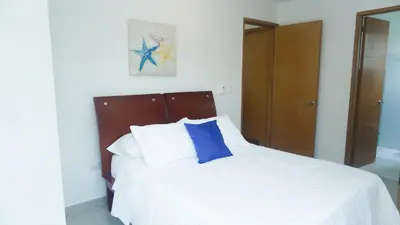a bedroom with a white bed with a blue pillow at Hermoso Apartamento Frente al Mar 2 Habitaciones B12B in Coveñas