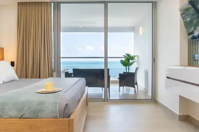 a bedroom with a bed and a view of the ocean at CB1004 Nueva Suite Frente al Mar - 2min Aeropuerto in Cartagena de Indias