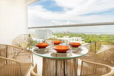 a balcony with a table with bowls and chairs at Cómoda Suite con Dos Camas Queen Piscina CB1031 in Cartagena de Indias