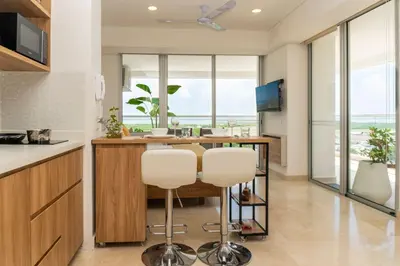 a kitchen with a table and two white stools at Comoda Suite Vista al lago-Amanecer hermoso CB1130 in Cartagena de Indias