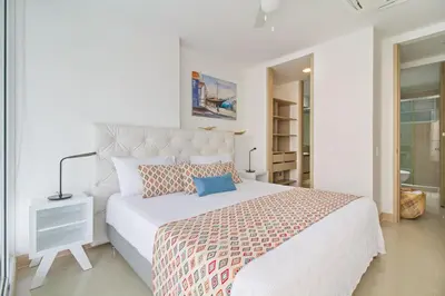a white bedroom with a large white bed with pillows at Descanso y playa, cómodo apartamento en Kuali, Santa Marta in Santa Marta