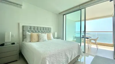 a bedroom with a white bed with a view of the ocean at Apartamento de una habitacion Palmetto Sunset 1703 in Cartagena de Indias