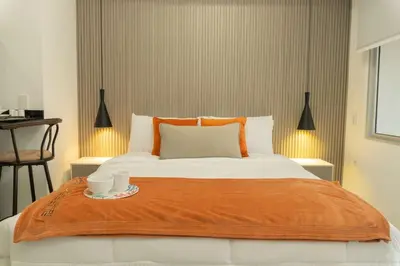 a bed with a orange blanket and two cups on it at Acogedora suite frente al mar + vista CB1427 in Cartagena de Indias