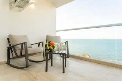 a room with two chairs and a table with flowers on it at Acogedora suite frente al mar + vista CB1427 in Cartagena de Indias