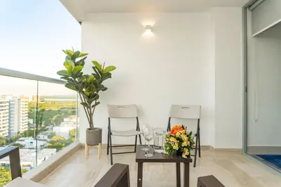 a dining room with two chairs and a table with flowers at Acogedora suite frente al mar + vista CB1427 in Cartagena de Indias