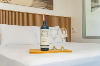 a bottle of wine and two wine glasses on a bed at Suite esquina con balcón y vista 180° al mar CB1429 in Cartagena de Indias