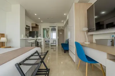 a bedroom with a bed and a kitchen with blue chairs at CB937 | Stylish loft piso 9 con balcón y vista ciudad in Cartagena de Indias