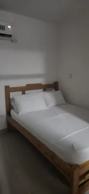 a wooden bed with white sheets and pillows at Caribe campestre coveñas in Coveñas